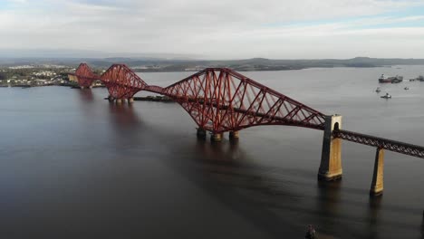 Drone-shot-of-a-train-crossing-the-the-Forth-Bridge-in-Queensferry,-Scotland