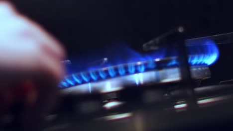 Slow-motion,-person's-hand-turning-off-stovetop-fire