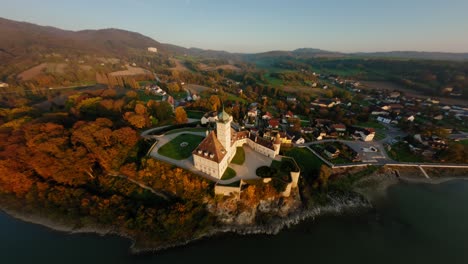 FPV-approaching-stunning-Schönbühel-castle,-diving-down-past-it,-showing-the-beautiful-Danube-river-during-autumn-Sunset
