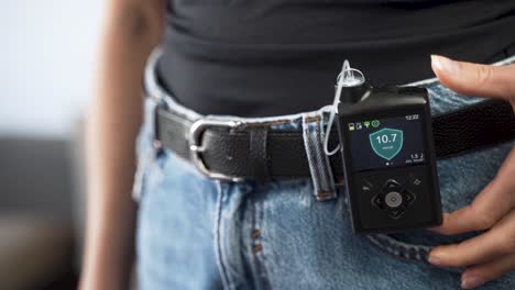 Diabetic-female-reaching-for-insulin-pump-on-her-waist-belt,-close-up