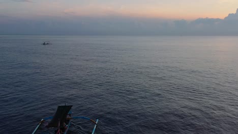 Luftzoom-Aus-Dem-Endlosen-Blauen-Ozean-Mit-Einem-Einzigen-Indonesischen-Jukung-Boot-Am-Horizont-Bei-Sonnenaufgang-In-Lovina-Bali-Indonesien