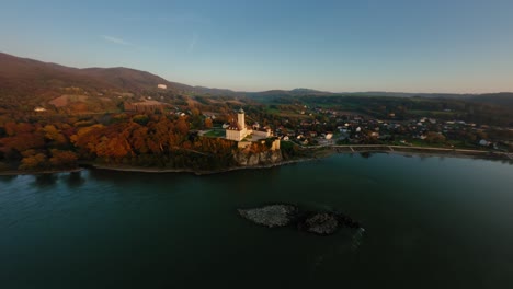 Beautiful-distant-FPV-roundshot-of-castle-Schönbühel,-appoaching-it-and-diving-down-next-to-it-toward-the-evening-Danube-valley,-Wachau,-Austria