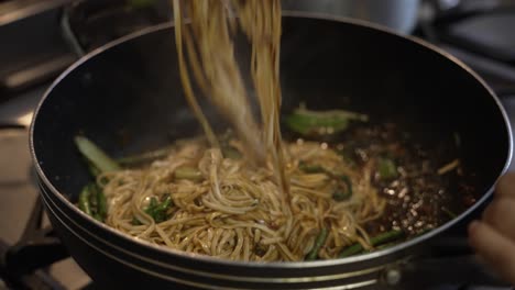 Chef-Using-Metal-Tongs-To-Toss-And-Stir-Noodles-Inside-Hot-Wok