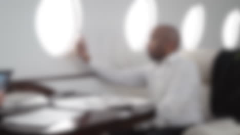 Blurred-shot-of-an-african-american-businessman-working-in-his-private-jet,-traveling-and-working-concept