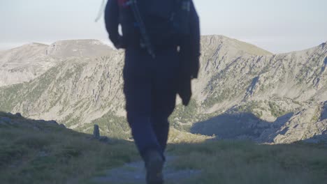 a-man-trekking-alone-in-the-mountains-,walking-away-from-the-camera