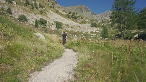 a-man-hiking-alone-on-a-mountains-trail-with-hiking-poles,-walking-towards-the-camera