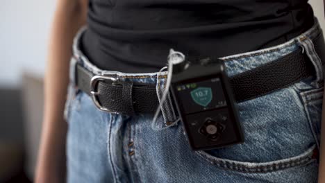Diabetic-female-switching-on-insulin-pump-on-her-waist-belt,-close-up