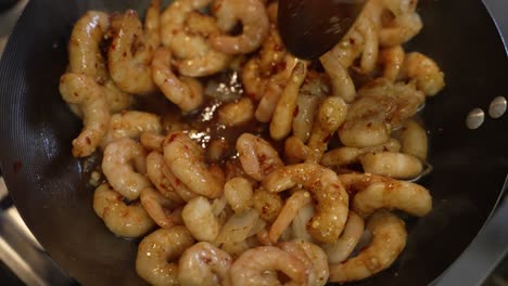 Overhead-View-Of-Frozen-Prawns-Being-Stirred-And-Shaken-Inside-Wok-With-Wooden-Spoon