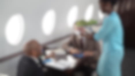 Blurred-shot-of-businessmen-having-a-meeting-and-eating-in-a-private-jet-during-a-business-flight
