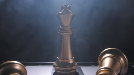 Gold-king-on-chess-board-last-one-standing,-dramatic-twirling-smoke-background