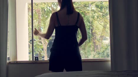 rear-view-of-a-lady-in-shorts-and-t-shirt-opening-a-bedroom-window-overlooking-the-garden