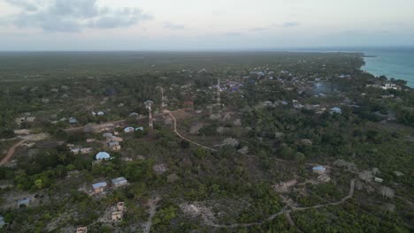 Three-communication-towers-on-Kusini-beach-town-in-East-Zanzibar-Island-Tanzania-Africa,-Aerial-flyover-shot
