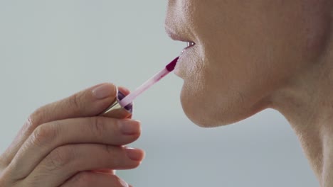 Close-up-on-lips,-side-view-of-woman-applying-lipstick-indoors-in-slow-motion