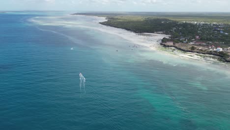 Kusini-beach-in-East-Zanzibar-Island,-Tanzania-Africa,-with-boat-advancing-over-coral-reef,-Aerial-flyover-shot