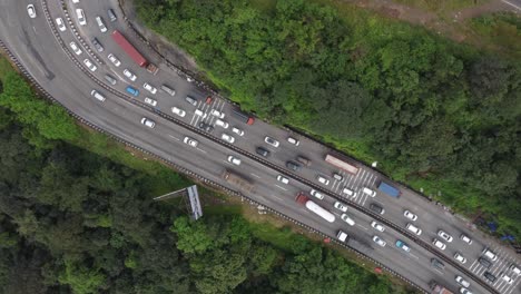 Top-down-aerial-drone-shot-of-beautiful-expressway-interchange-with-lots-of-cars-and-heavy-transportation-vehicles-crossing-each-other-carved-through-deep-valley
