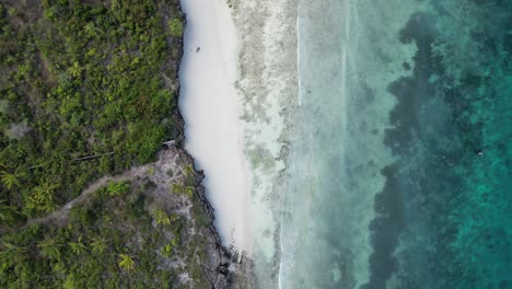 Kusini-beach-in-East-Zanzibar-Island-Tanzania-Africa-with-coral-reef-and-rocky-shore,-Aerial-looking-down-rotation-shot