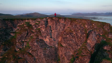 Pullback-Aufnahme-Eines-Mannes-Aus-Der-Luft,-Der-Auf-Dem-Gipfel-Einer-Bergwelle-Steht,-Zur-Kamera,-Bevor-Sie-Sich-Zurückzieht,-Um-Eine-Wunderschöne-Berglandschaft-An-Der-Küste-Zu-Enthüllen,-Matinden-Auf-Andoya-In-Norwegen