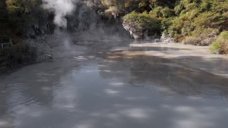 Aerial-push-out-shot-above-the-boiling-mud-pools-at-Waiotapu,-Rotorua,-New-Zealand