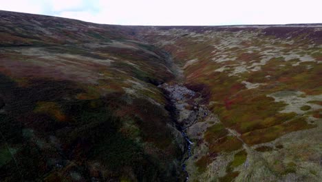 slow-drone-shot-looking-up-a-lush-multi-coloured-valley-in-the-english-moorlands-of-Manchester