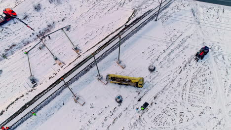 Aerial-top-down-shot-of-industrial-workers-checking-cable-overhead-wire-of-train-railroad-in-winter