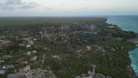 Kusini-beach-town-in-East-Zanzibar-Island-Tanzania-Africa-with-communication-towers-and-resorts,-Aerial-flyover-shot