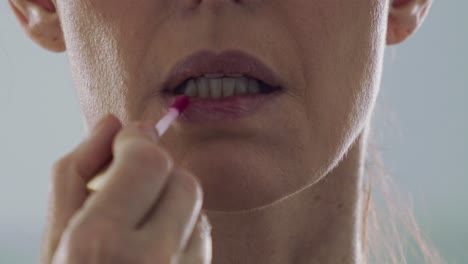 Close-up,-middle-aged-brunette-woman-applying-lipstick-in-slow-motion