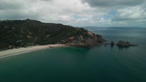 Scenic-drone-flight-around-rock-face-in-the-Coromandel-Peninsula-at-Otama-beach