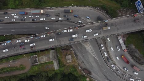 Beautiful-top-down-aerial-view-of-expressway-interchange-with-cars-and-heavy-transportation-vehicles-crossing-each-carved-through-deep-valley