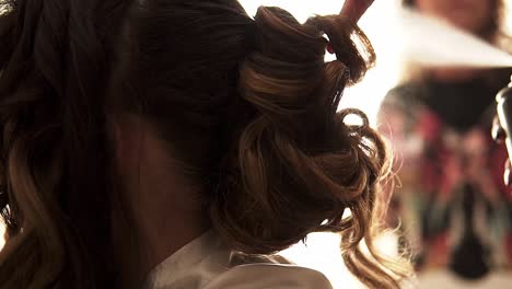 Slow-motion-handheld-shot-of-a-hairdresser-styling-a-bride's-hair-before-her-wedding-and-spraying-it-with-hairspray