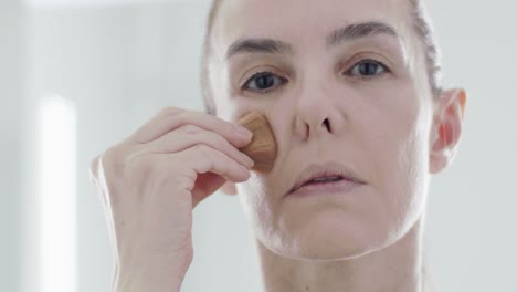 Kaukasische-Frau-40er-Jahre,-Die-Bürste-Verwendet,-Um-Grundierung-Auf-Ihrem-Gesicht-Für-Gesichtspflege-Und-Anti-falten-Aufzutragen