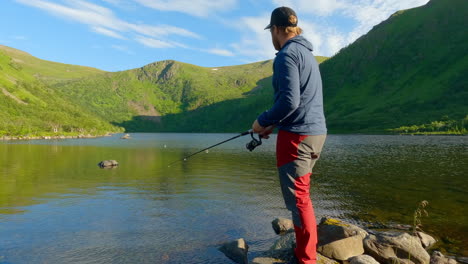 shot-of-a-man-fishing-over-the-lake-in-the-summer-at-Vesteralen-Andoya,-Norway