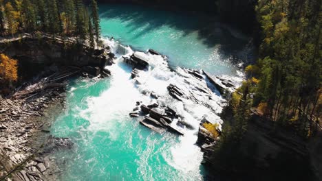 aerial-zoom-out-shot-of-Rearguard-Falls-drone-flying-past-trees-towards-the-waterfalls-on-a-sunny-day-in-autumn-in-a-forest-environment-and-the-fraser-river