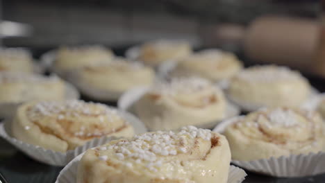 Static-close-up-of-cinnamon-buns-with-focus-pulling-and-baking-utensils-in-the-background