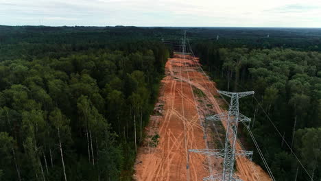 Aerial-flyover-connected-electricity-pylons-surrounded-by-deep-forest-woodland