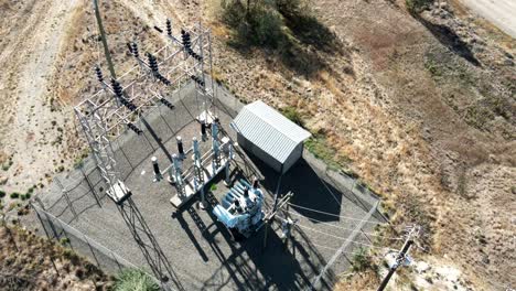 pan-left-aerial-zoom-shot-of-an-electric-transformer-station-with-a-small-building-in-a-desert-environment