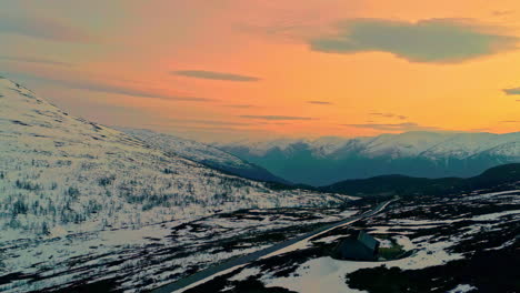 Un-Dron-Aéreo-Disparó-Sobre-Una-Cabaña-De-Madera-Rodeada-De-Una-Meseta-Montañosa-Rodeada-Por-Una-Hermosa-Cordillera-Noruega