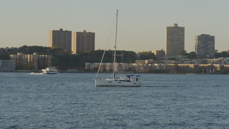 Segelboot-Mit-Einzelmast,-Das-Entlang-Der-Ruhigen-Gewässer-Des-Hudson-River-Navigiert,-Mit-New-Jersey-Im-Hintergrund