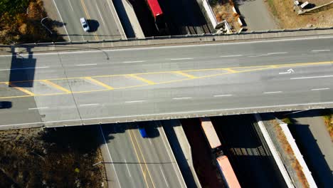 normal-speed-bird's-eye-view-static-drone-shot-of-Bridge-of-the-Highway-1-and-Yellowhead-Highway-in-Kamloops-BC-Canada-with-trains-and-vehicles-moving-one-the-streets-on-a-sunny-day