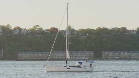 Sailboat-With-Single-Mast-Navigating-Along-The-Hudson-River-During-Sunset-With-New-Jersey-In-The-Background
