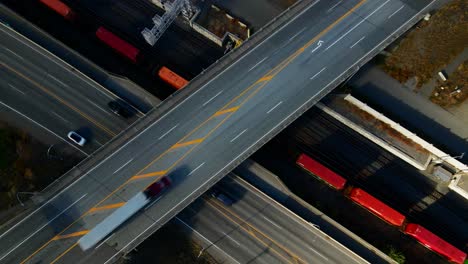 normal-speed-bird's-eye-zoom-out-drone-shot-of-Bridge-of-the-Highway-1-and-Yellowhead-Highway-in-Kamloops-BC-Canada-with-trains-and-vehicles-moving-one-the-streets-on-a-sunny,-colourful-day