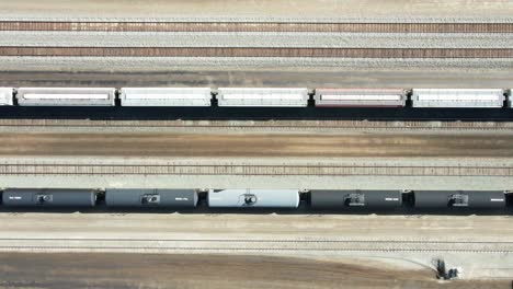bird's-eye-view-truck-sideways-drone-shot-flying-over-railroad-station-in-a-desert-environment-on-a-sunny-day-with-cargo-and-tank-tains