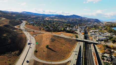 dolly-out-drone-shot-hyperlapse-of-Kamloops-BC-Canada-with-Bridges-and-the-Highway-1-and-Yellowhead-Highway-5-on-a-sunny-day-in-the-desert-city-with-cars-and-semi-trucks-driving-in-the-foreground