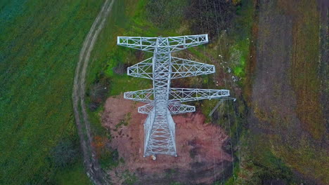 Aerial-drone-tilt-down-shot-over-a-newly-constructed-electric-pole-for-placing-electric-lines-through-green-grasslands-at-daytime