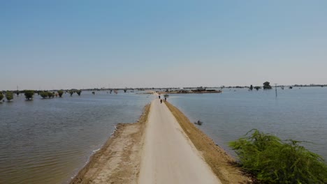 Aerial-Flying-Along-Only-Road-Through-Flooded-Landscape-In-Maher,-Sindh