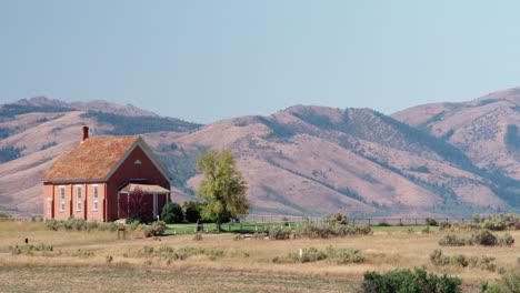 And-old-building-on-a-hill-overlooking-the-mountains-and-sagebrush-valley-in-Chesterfield,-Idaho