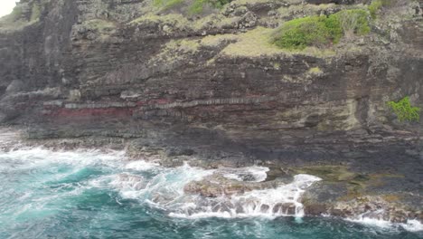Cinematic-azure,-blue,-green,-turquoise-waves-crashing-on-scenic-black-volcanic-sea-cliffs-and-sharp-rocks