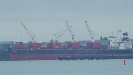 Large-cargo-vessel-loading-goods-at-Port-of-Liepaja-,-overcast-day,-distant-shot