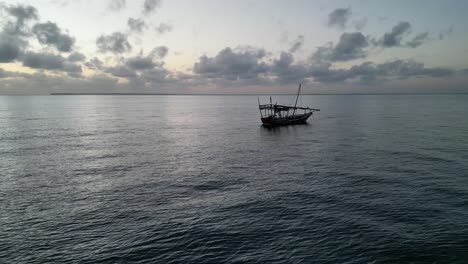 Barco-Flotando-Cerca-De-La-Playa-De-Uroa-En-La-Isla-De-Zanzíbar,-Tanzania-áfrica-Durante-La-Puesta-De-Sol,-Tiro-Aéreo-A-La-Derecha