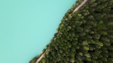 Flying-upwards-will-slowly-spinning-over-blue-lake-with-forest-and-pathway