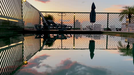 Tranquil-scene-of-Sunset-sky-reflected-over-a-rooftop-swimming-pool-surface,-Static-shot